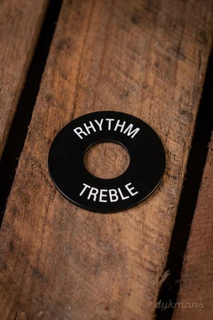 Gibson PRWA-020 zwart schakelaarplaatje met witte RHYTHM- en TREBLE-opdruk op een houten ondergrond